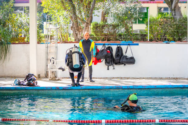 istock three divers on the shore of a pool while one of them is jumping into it and another is already swimming in the water 1292811527