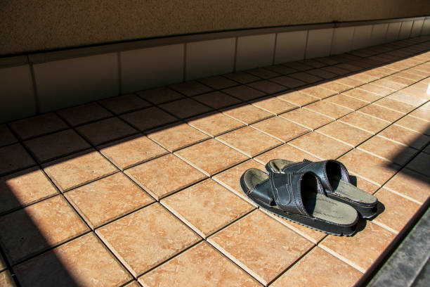 A pair of used clogs or sandals of synthetic material on a coloured cobbled cement surface