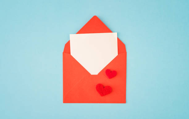 istock Red paper envelope with blank white note mockup inside and Valentines hearts on blue background 1292812990