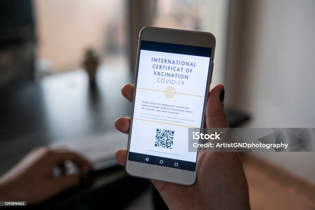 Mobile App For International Certificate of Vaccination for COVID-19 Cropped hand holding smart phone with mobile app on the screen for covid-19 vaccination certificate. Airplane Ticket Stock Photo