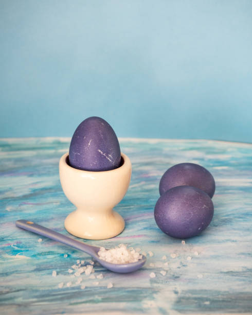 fioletowe jajka w uchwycie jaj z ceramiczną łyżką na niebieskim tle - on eggs standing spoon zdjęcia i obrazy z banku zdjęć