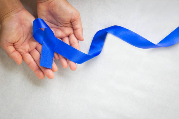 Hands holding deep blue ribbon on white fabric with copy space. Colorectal Cancer Awareness, Colon cancer of older person and world diabetes day, Child abuse prevention. Healthcare, insurance concept. manos sosteniendo cinta azul profundo sobre tela blanca con espacio de copia. concientización sobre el cáncer colorrectal, cáncer de colon de personas mayores y el día mundial de la diabetes, prevención del abuso infantil. salud, concepto de seguro.