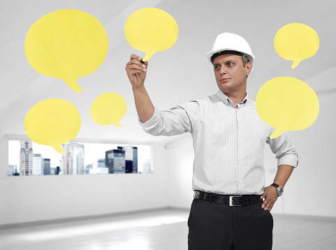 Architect wearing a helmet writing on speech bubble adhesive notes