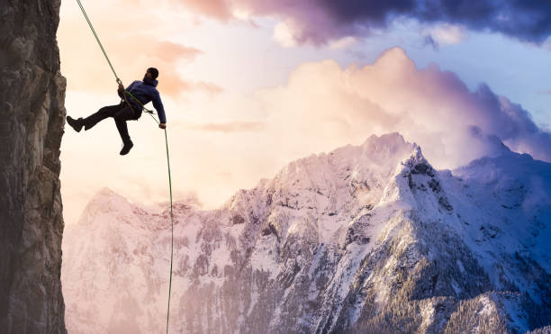 epic adventurous extreme sport composite of rock climbing man rappelling from a cliff - rock climbing fotos imagens e fotografias de stock
