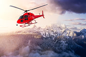 Red Color Helicopter flying over the Rocky Mountains