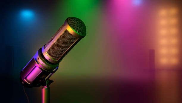 istock Microphone in bright spotlights on a smoky background with multicolored beams. Light show. 1292836059