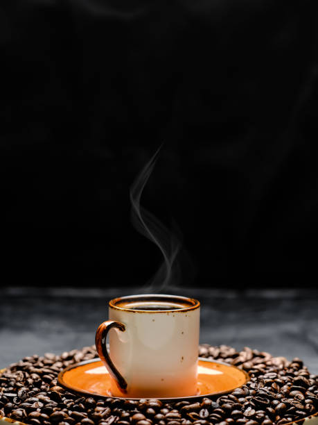 Cup with coffee espresso arranged on a dark background. Roasted coffee beans are located around a cup of coffee.Close up, selective focus stock photo
