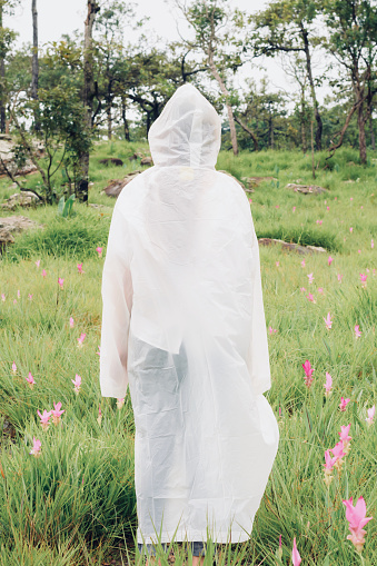 woman wear raincoat stand back in the rainforest
