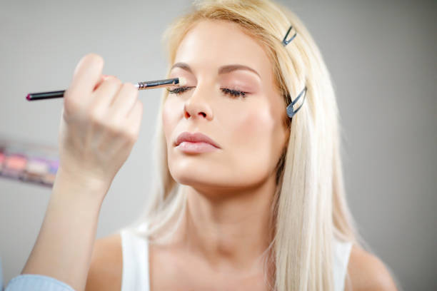 istock Beautiful blond woman on make-up session, eye shadow applied 1292850215