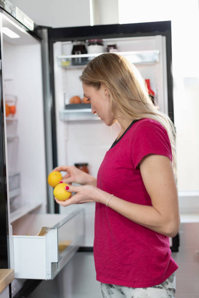 istock Woman by the open fridge taking lemon from drawer 1292851671