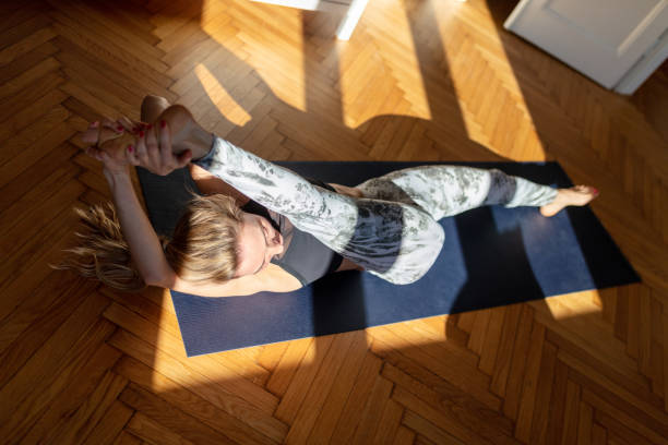 istock Woman doing yoga at home, stretching hamstrings, one leg up, lying on back 1292853278