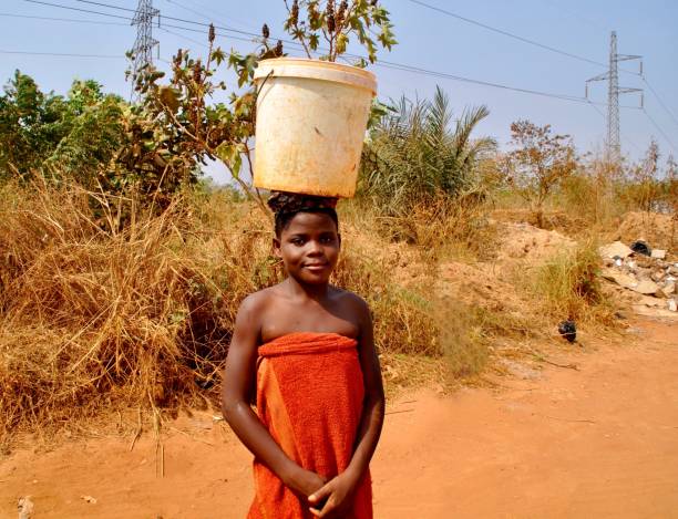 une fille avec un seau d’eau sur la tête - porter sur la tête photos et images de collection