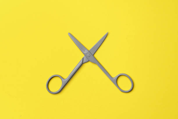 istock Gray scissors on yellow background top view 1292856927