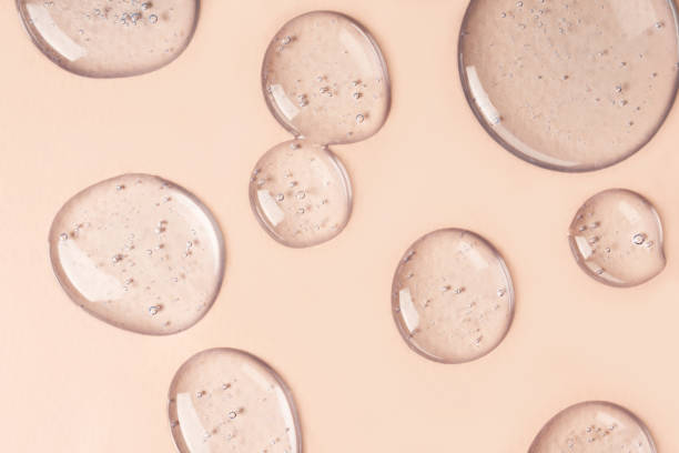 Drops and smears of cosmetics. Drops of liquid transparent gel with bubbles on a brown background. Drops and smears of cosmetics. Drops of liquid transparent gel with bubbles on a brown background face serum stock pictures, royalty-free photos & images