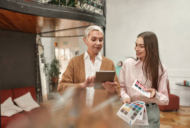 istock Two well-dressed female collaborateurs smiling speaking to each other with a tablet in hands 1292858462