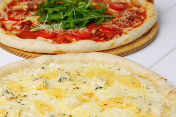 Two fresh pizzas on white wooden table close up photo