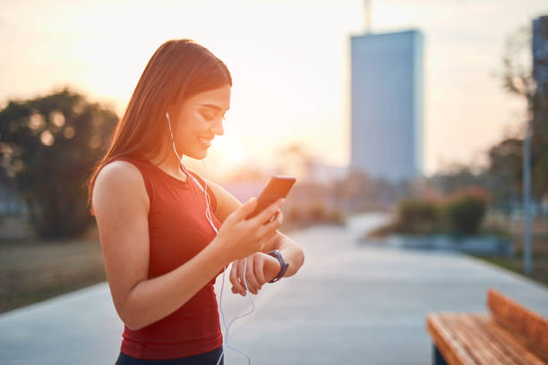 istock Modern young woman with cellphone making pause during jogging / exercise. 1292862156