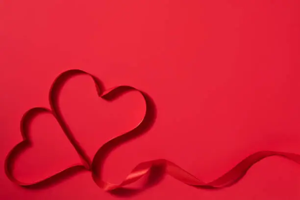 Photo of Valentine's day background with heart shape decorations and ribbons. View from above. Flat lay composition on red