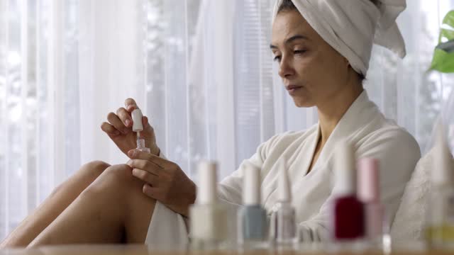 Women beauty treating herself by polish fingernails after bath