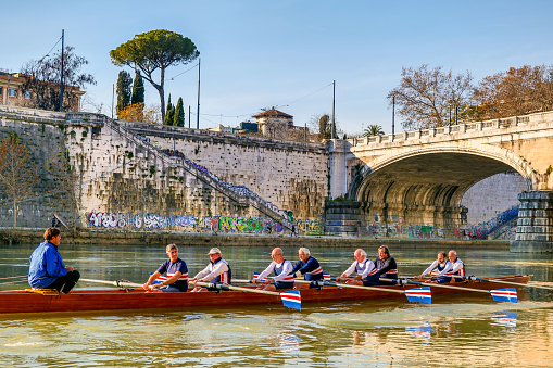 Rome, Italy, December 21 -- A team of senior rowers, made up of middle-aged and senior men, during a training session along the placid waters of the Tiber River in the center of Rome. Image in High Definition format.