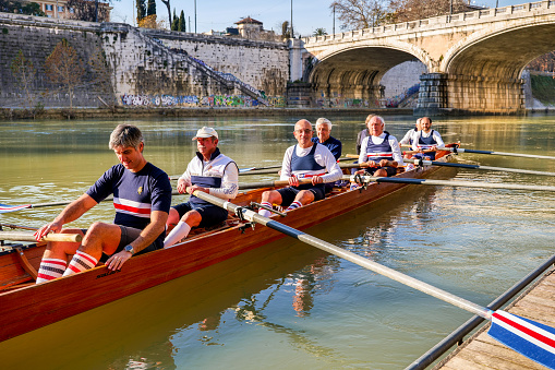 Rome, Italy, December 21 -- A team of senior rowers prepares to leave the riverbank for a training session along the placid waters of the Tiber River in the center of Rome. Image in High Definition format.