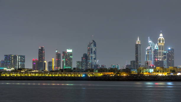 istock Modern Dubai city skyline at night with illuminated skyscrapers over water surface 1292866421
