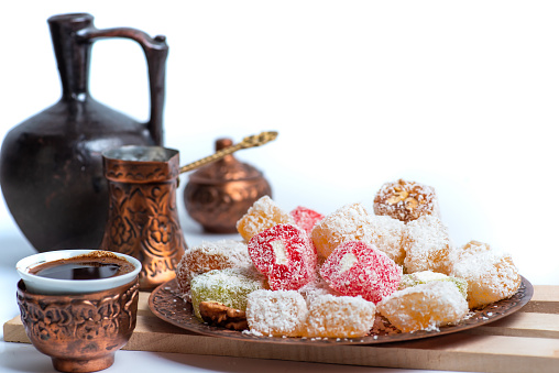 Traditional Turkish delights desserts covered with coconut powder and Turkish coffee on a rustic plate top view