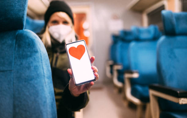 A young urban woman holding a smartphone with a red heart shape on a screen display. Place for copy space on the device's screen.Focus on foreground
