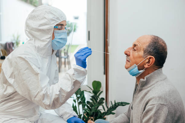 istock Protected health professional Testing for Coronavirus a patient in a home visit. 1292879667
