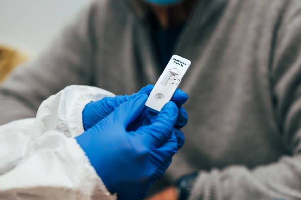 Negative results of a Rapid Antigen Test for SARS Covid-19. Close up of doctor hands with protective gloves and PPE suit, showing a test device to senior patient. Review of a Rapid Antigen Test for SARS Covid-19. antigen photos stock pictures, royalty-free photos & images