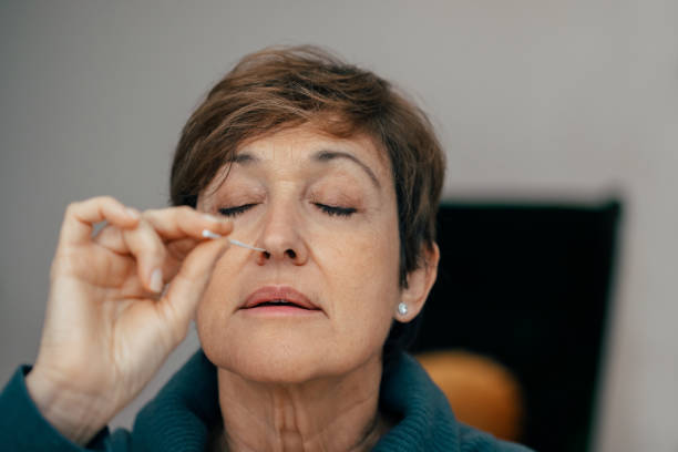 istock Senior woman using an nasal swab for covid 19 detection, self testing. 1292879791