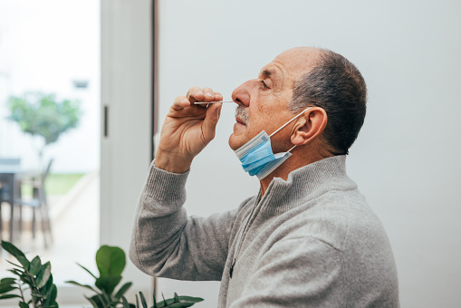 Un hombre de la tercera edad usando un hisopo nasal para la detección de covid 19. photo