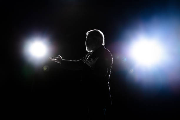istock Elderly man silhouette gesturing isolated on dark background. 1292881590