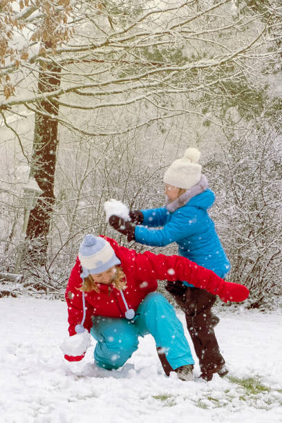 mujer joven con un niño, niña de 5 años caucásica. mamá e hija hacen un muñeco de nieve y tiran nieve. diversión y diversión los fines de semana en invierno. - 35 40 years fotografías e imágenes de stock