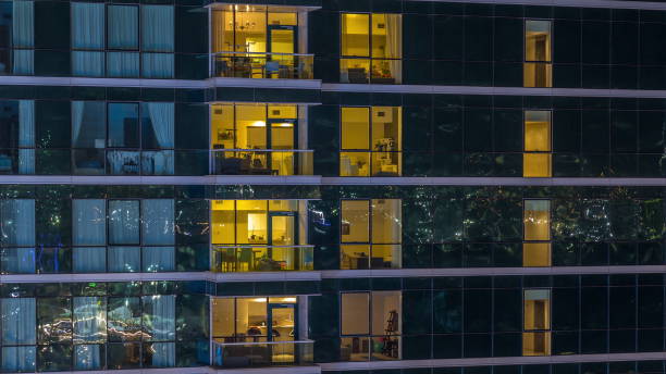 istock Glowing apartment windows at night in glass skyscraper timelapse 1292894884