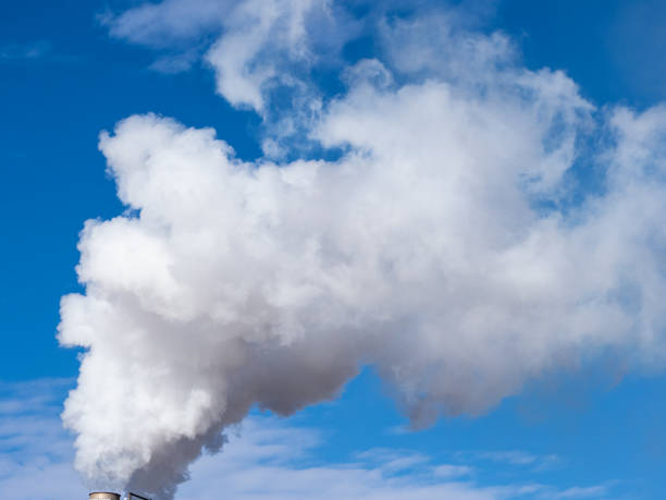 istock Chimney spewing polluting smoke into a blue sky. 1292899324