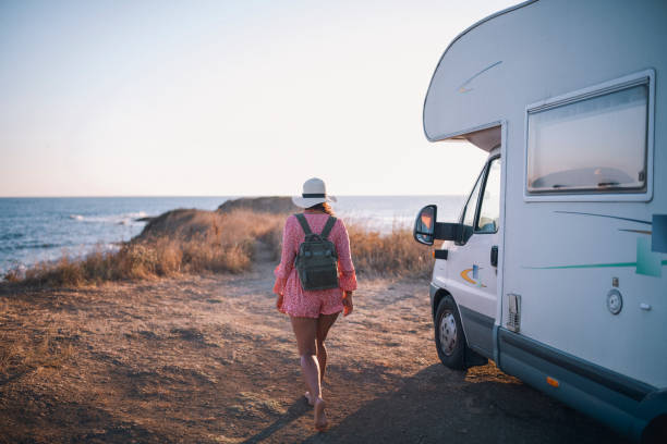 istock Female Traveler With A Straw Hat And A Backpack Is Walking Next To Her Camper 1292903488