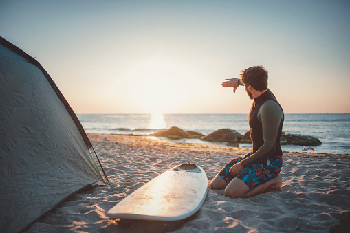 Male surfer preparing his surfboard for riding.