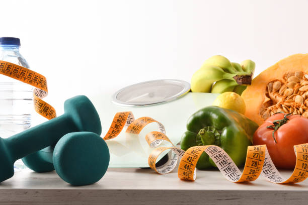 istock Vegetables and fruits on table with dumbbells and scale isolated 1292904201