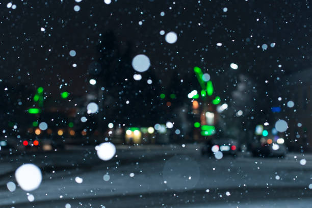 istock Blurred background with falling snow and city lights in winter 1292904563