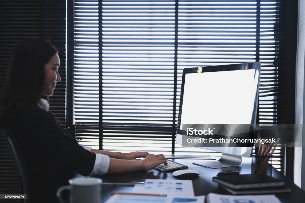 A concentrate businesswoman using computer and  analysis investment with chart at office desk. Adult Stock Photo