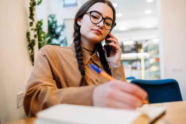 istock Young woman with glasses writes in a notebook 1292906204