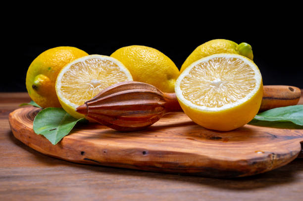 limoni italiani gialli freschi maturi e spremiagrumi di legno, nuova vendemmia - neapolitan specialty foto e immagini stock