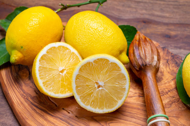 свежие спелые желтые итальянские лимоны и выжимка из деревянного сока, новый урожай - neapolitan specialty стоковые фото и изображения