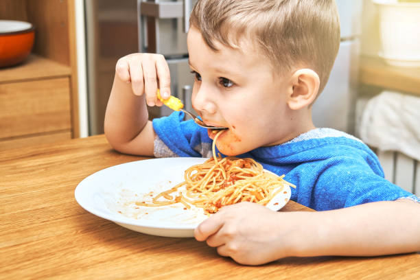 istock Lovely kid with large eyes eats sloppy delicious pasta 1292907564
