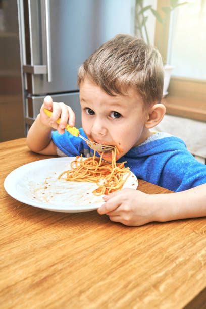 istock Lovely kid with large eyes eats sloppy delicious pasta 1292908190