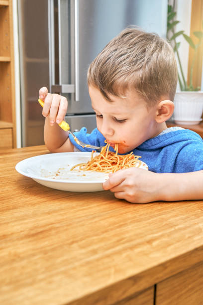 istock Lovely kid with large eyes eats sloppy delicious pasta 1292908206