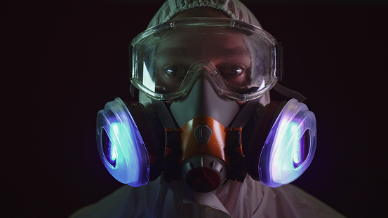 Man in protective costume suit, gas protect medical antibacterial antiviral spray paint mask. Doctor health worker in respirator. Concept health virus coronavirus epidemic. Radiation Nuclear war.