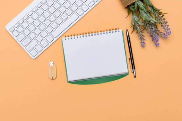 istock Home office workspace with computer keyboard, blank paper clipboard and green plant on cream color background. Flat lay, top view. Working home concept. 1292913616