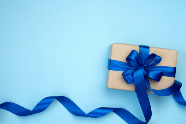 istock Gift box with blue ribbon bow isolated on blue background. 1292915025